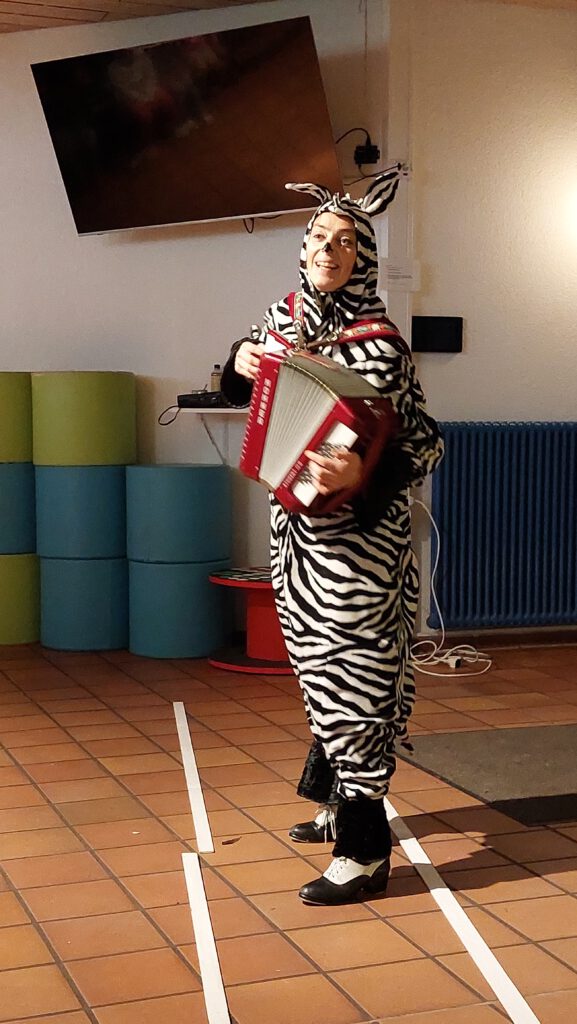 Eine als Zebra verkleidete Frau spielt Akkordeon