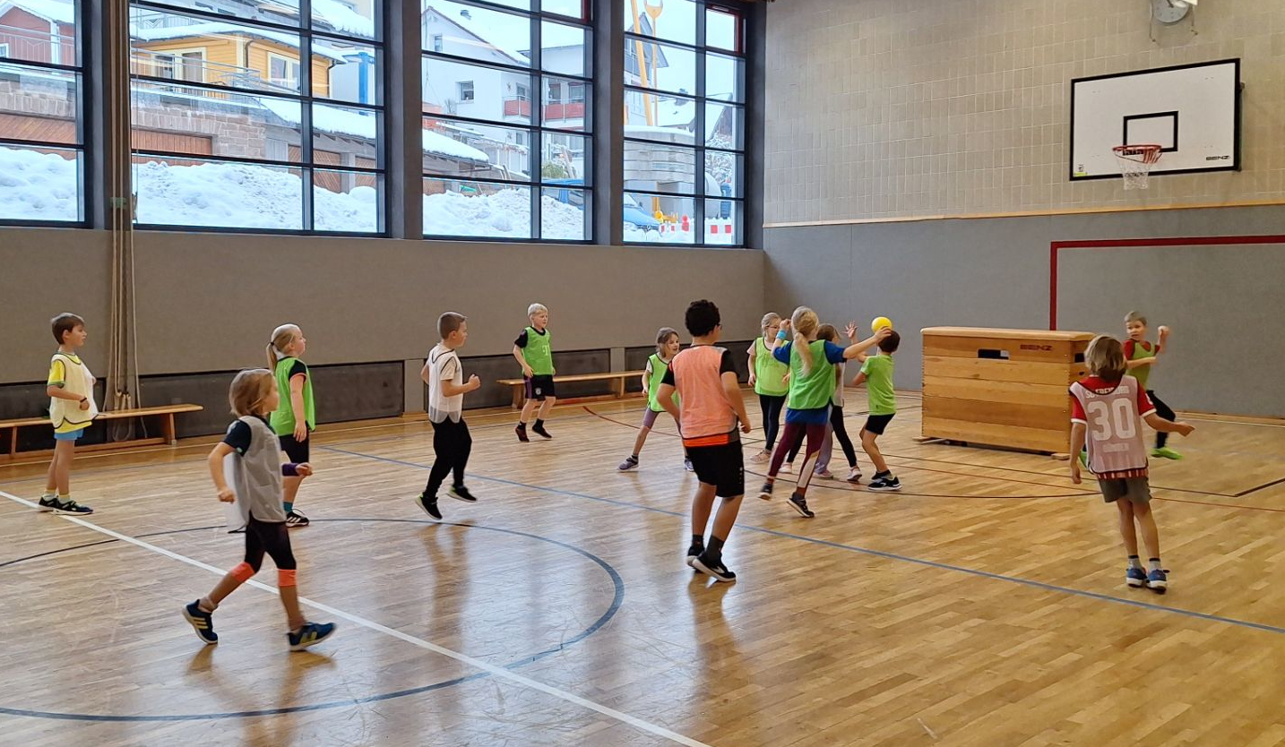 Kinder spielen in der Turnhalle Handball